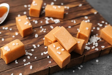 Delicious caramel candies with salt on wooden board
