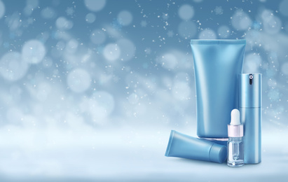 Different cosmetic products on blue background with blurred snowflakes, space for text. Winter skin care