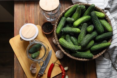 Fresh cucumbers, other ingredients and jars on wooden table, flat lay. Pickling vegetables