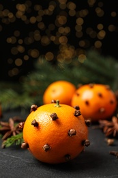 Delicious fresh tangerines with cloves on black table. Christmas celebration
