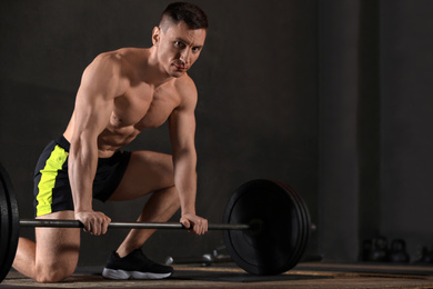 Strong man lifting barbell in modern gym