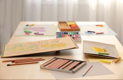 Artist's workplace with drawings, soft pastels and color pencils on table indoors