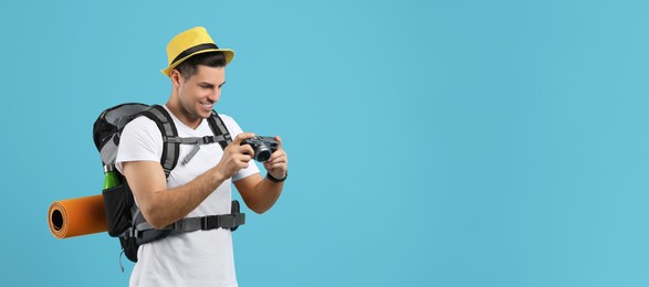 Male tourist with travel backpack and camera on turquoise background