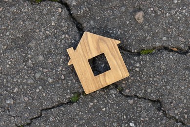 Wooden house model on cracked asphalt, top view. Earthquake disaster