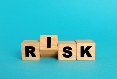 Word Risk made of wooden cubes on turquoise background