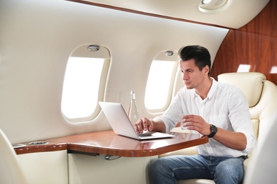 Handsome man working with laptop on plane. Comfortable flight