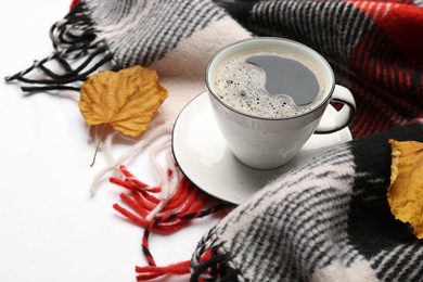 Composition with hot drink and warm plaid on white bedsheet