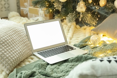 Modern laptop on plaid near Christmas tree