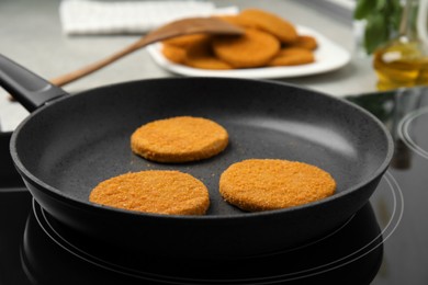 Cooking breaded cutlets in frying pan on stove
