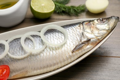 Photo of Delicious salted herring and ingredients on wooden table, closeup