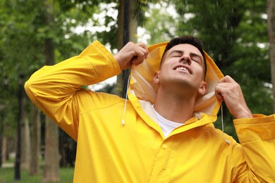 Man with raincoat walking under rain in park