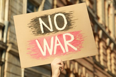 Woman holding poster with words No War outdoors