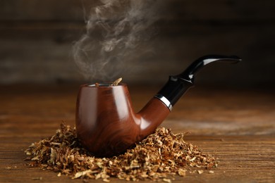 Classic smoking pipe with tobacco on wooden table
