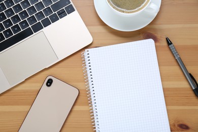 Empty notebook, laptop, coffee and smartphone on wooden table, flat lay