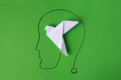 Photo of Drawn human head with white paper bird as solution idea on green background, top view