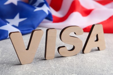 Word Visa and American flag on light grey table, closeup