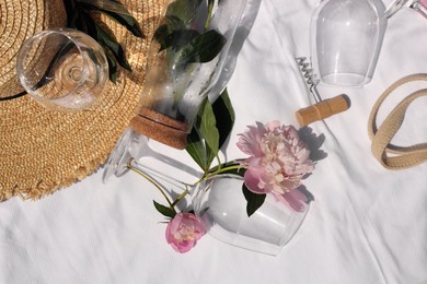 Flat lay composition with beautiful peonies and wineglasses on white fabric