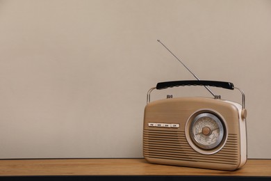 Retro radio receiver on wooden table against grey background. Space for text
