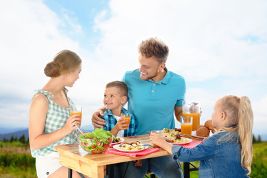 Image of Happy family having picnic at table in park