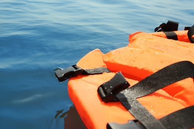 Orange life jacket floating in sea, closeup. Emergency rescue equipment