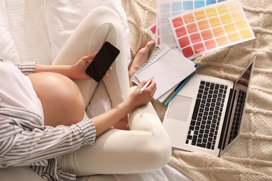 Pregnant woman working on bed at home, above view. Maternity leave
