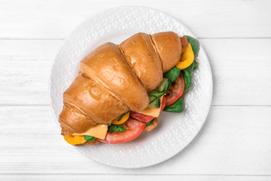 Tasty vegetarian croissant sandwich on white wooden table, top view