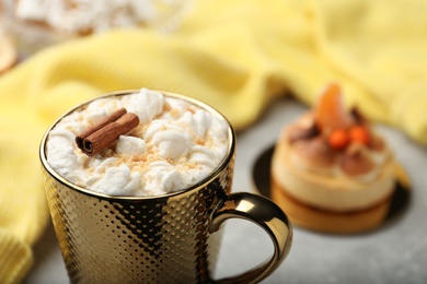 Delicious marshmallow drink with cinnamon in cup on blurred background, closeup
