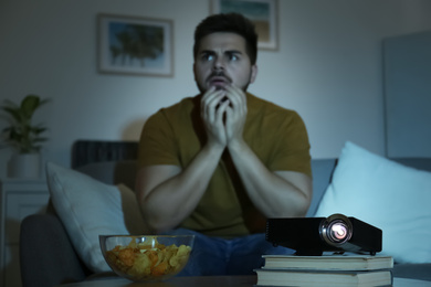 Young man watching movie at home, focus on video projector