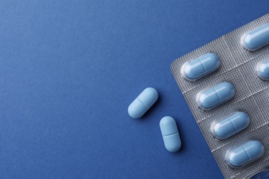 Photo of Pills and space for text on blue background, top view. Potency problem