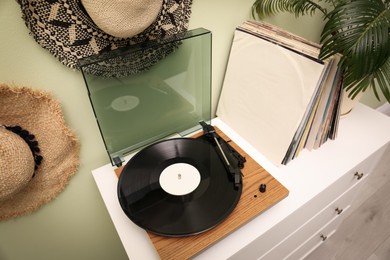 Turntable and collection of vinyl records on white dresser indoors