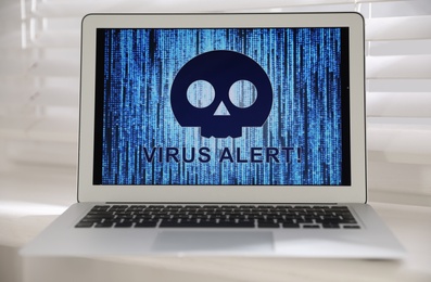 Laptop with warning about virus attack on window sill