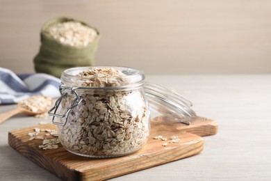 Glass jar with oatmeal on white wooden table. Space for text
