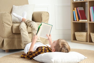 Little boy reading book on floor at home