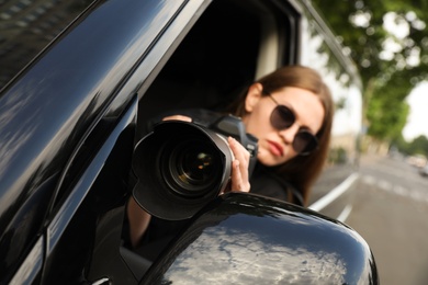 Private detective with modern camera spying from car, focus on lens