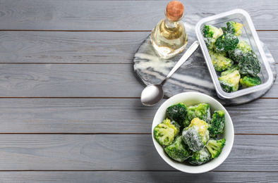 Flat lay composition with frozen broccoli on light grey wooden table, space for text. Vegetable preservation