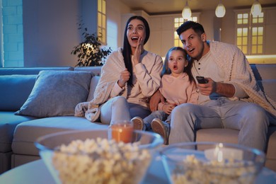 Family watching movie on sofa at night
