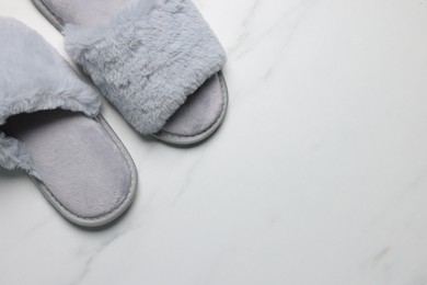 Pair of soft slippers on white marble floor, top view, closeup. Space for text