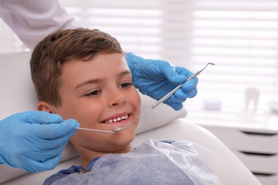 Dentist examining little boy's teeth in modern clinic