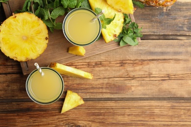 Photo of Delicious fresh pineapple juice on wooden table, flat lay. Space for text