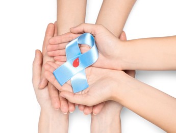 People holding light blue ribbon with paper blood drop on white background, top view. World Diabetes Day