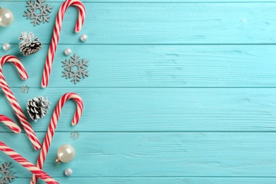 Flat lay composition with candy canes and Christmas decor on cyan wooden table. Space for text