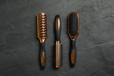 Set of hair brushes on black slate background, flat lay