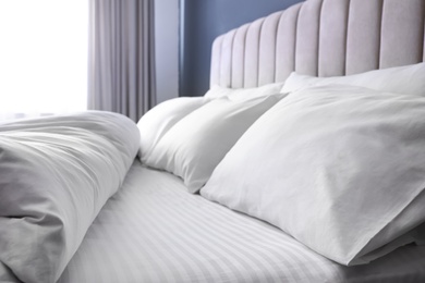Photo of Comfortable bed with soft pillows indoors, closeup
