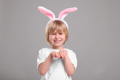 Photo of Happy boy wearing bunny ears headband on grey background. Easter celebration