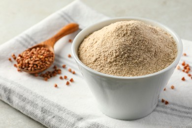 Bowl of flour and spoon with buckwheat on cloth