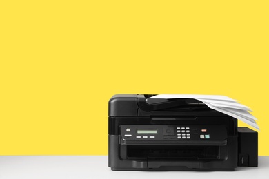 Photo of New modern printer with paper on yellow background. Space for text