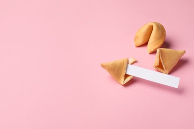 Tasty fortune cookies with predictions on pink background, space for text