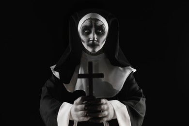 Scary devilish nun with cross on black background. Halloween party look