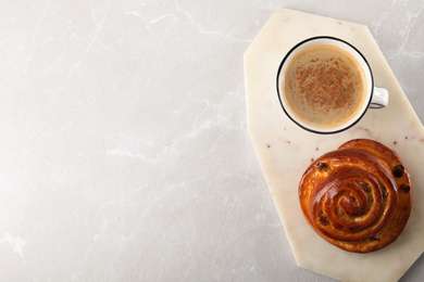 Delicious coffee and bun on marble table, top view with space for text. Sweet pastries
