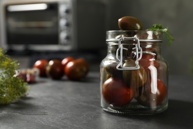 Pickling jar with fresh tomatoes on black kitchen table, closeup. Space for text